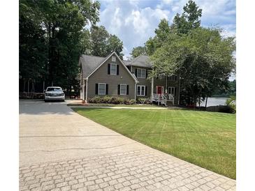 Charming two-story home with a well-manicured lawn and a brick-paved driveway, surrounded by mature trees and a view of the lake at 25 Clay Ct, Hiram, GA 30141
