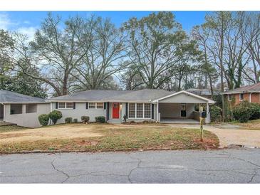 Charming single-story home featuring a well-maintained lawn, covered parking and a vibrant red front door at 2917 Toney Dr, Decatur, GA 30032