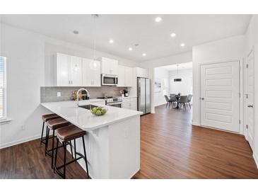 Modern kitchen with stainless steel appliances, a large island with seating, and sleek white cabinetry at 804 White St, Villa Rica, GA 30180