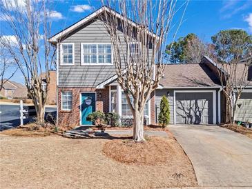 Charming two-story townhouse featuring a brick facade, gray siding, well-manicured lawn and an attached garage at 102 Johnson Ct, Decatur, GA 30030