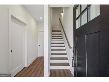 Bright foyer with wood floors leads to a staircase with a wood handrail and white risers at 310 Mcdonough Se Blvd # 104, Atlanta, GA 30315