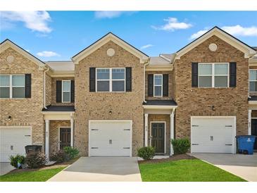 Charming brick townhome featuring a one-car garage, manicured lawn, and inviting front entrance at 815 Taurus Dr, Stockbridge, GA 30281