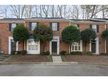 Charming brick townhome featuring black shutters and a well-maintained front yard with mature trees at 1160 Windsor Pkwy # 13, Atlanta, GA 30319