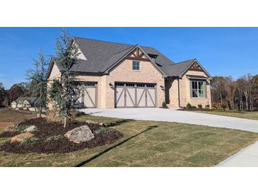 Craftsman-style home featuring a three-car garage, brick facade, and manicured front lawn at 2235 Windsor Bluffs Dr, Cumming, GA 30041