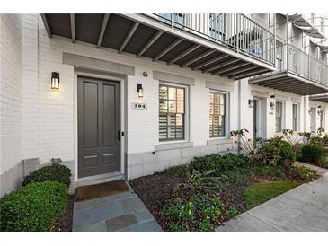 Charming townhome featuring brick facade, gray door, lush landscaping and private balcony at 304 Stonemont Dr, Atlanta, GA 30305