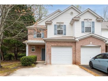 Charming two-story townhome features a brick facade, light siding, attached garage and well-maintained landscaping at 131 Ellis Dr, Conyers, GA 30012