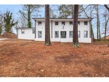 Beautiful two-story home featuring a freshly painted white brick exterior, black trim, and mature trees at 2670 Thornbury Way, Atlanta, GA 30349