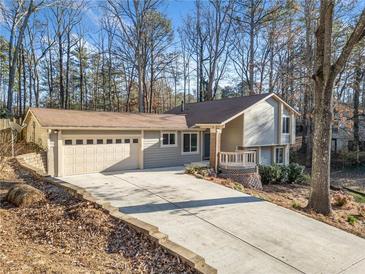 Charming home featuring a spacious driveway and attached garage against a backdrop of lush, mature trees at 6817 Knollwood Dr, Douglasville, GA 30135