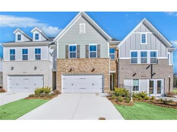 Charming townhome exterior featuring a brick facade and two-car garage at 5619 Tillman Way, Powder Springs, GA 30127