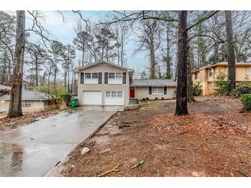 Split-level home with white brick, black shutters, two-car garage, and red front door at 2202 Troutdale Dr, Decatur, GA 30032