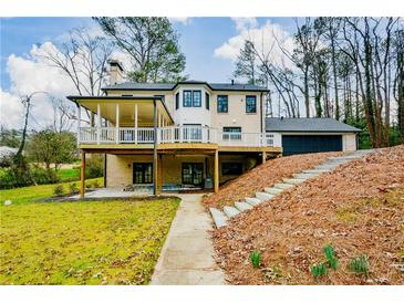 Expansive rear exterior featuring an elevated deck, patio, and stairs ascending towards the attached garage at 805 Wesley Oak Rd, Atlanta, GA 30328