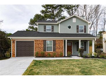 Charming two-story home with brick accents, a well-manicured lawn, and an attached garage at 6242 Marbut Farms Ln, Lithonia, GA 30058