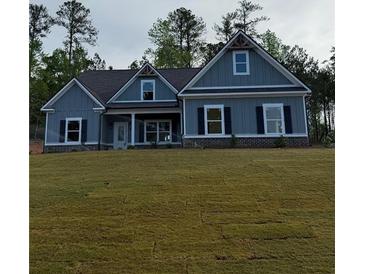 Charming single-Gathering home featuring blue siding, black shutters, a covered porch, and a well-manicured front lawn at 1130 Holly Dr, Loganville, GA 30052