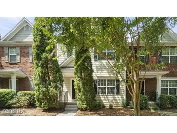 Charming townhome featuring a mix of brick and siding, complemented by mature trees and well-maintained landscaping at 1202 Charleston Ct Cir, Woodstock, GA 30188