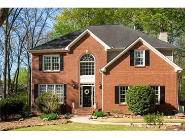 Charming two-story brick home with a welcoming front door, black shutters, and lush green lawn at 6435 Ivey Creek Cir, Cumming, GA 30040