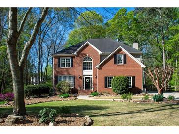 Charming red brick two-story home with beautiful landscaping and a well-manicured lawn at 6435 Ivey Creek Cir, Cumming, GA 30040