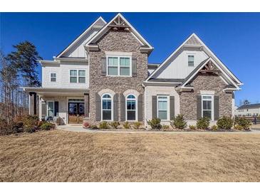 Stunning two-story home boasts a stone facade, gabled roof and a manicured lawn at 4205 Madison Hall Dr, Cumming, GA 30028