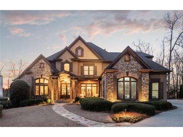 Stately stone and stucco home featuring a well-manicured lawn and elegant architectural details at 6955 Laurel Oak Dr, Suwanee, GA 30024