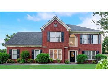 Charming two-story red brick home featuring lush landscaping and classic black window shutters at 3038 Mary Alice Trl, Loganville, GA 30052