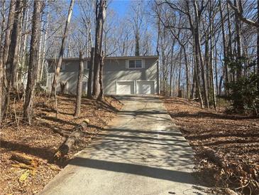 Two-story home with a long driveway leading to an attached two-car garage surrounded by trees at 5080 Springtree Ct, Lithonia, GA 30038