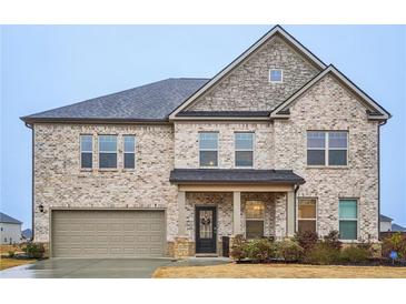 Beautiful two-story home featuring stone accents, brick, a covered porch, and an attached two-car garage at 938 Blue Juniper Cir, Loganville, GA 30052