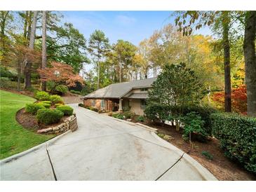 Charming one-story home with lush landscaping and a long driveway surrounded by mature trees at 5525 Whitner Dr, Sandy Springs, GA 30327