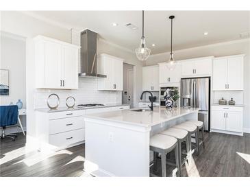 Bright, modern kitchen features white cabinets, stainless steel appliances, and a center island with bar seating at 216 Birchwood Row, Holly Springs, GA 30115