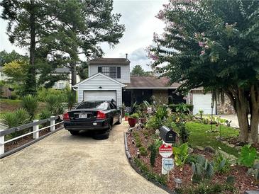 Charming home featuring mature landscaping, a long driveway, and an attached one-car garage at 709 Pine Tree Trl # 10A, Atlanta, GA 30349