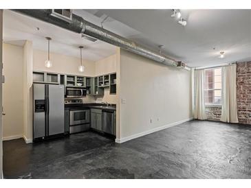 Spacious living room with kitchen, brick wall, natural light, and modern stainless steel appliances at 800 Peachtree Ne St # 8508, Atlanta, GA 30308