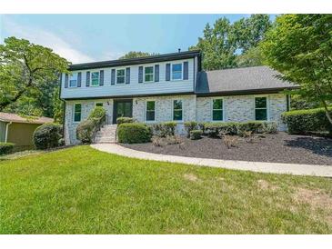 Charming two-story home featuring a brick facade, well-manicured lawn, and lush landscaping at 7602 Auden Trl, Atlanta, GA 30350