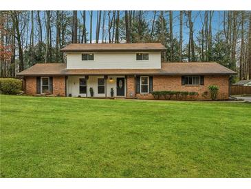 Two-story brick home featuring a large lawn and traditional design elements at 4072 Whispering Forest Ct, Lilburn, GA 30047