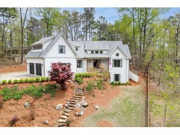 Charming two-story white home with a stone walkway and a two-car garage nestled in a lush, green landscape at 5975 P W A Dr, Cumming, GA 30041