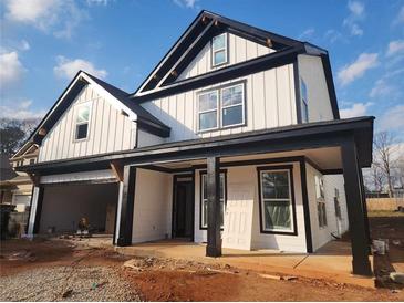 New two-story modern farmhouse featuring white siding, black trim, covered porch, and a two-car garage at 1064 Eastview Ne Rd, Conyers, GA 30012