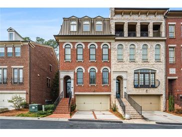 Charming brick townhome featuring arched windows, a two-car garage, and inviting entryway staircase at 3641 Broughton Se Cir, Atlanta, GA 30339