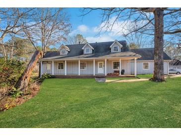 Charming single-story home with a well-manicured front lawn, welcoming front porch, and classic architectural details at 75 Price W Dr, Locust Grove, GA 30248