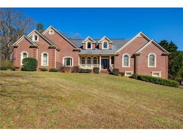 Stately brick home featuring dormer windows, arched windows, covered porch, manicured shrubs and lawn at 589 Cook Dr, Ellenwood, GA 30294