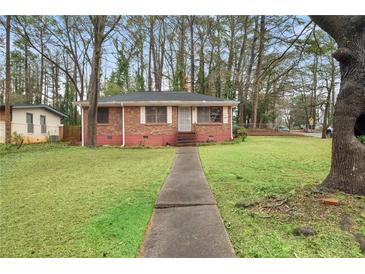 Charming brick home featuring a well-maintained front yard with mature trees at 1678 Capistrana Pl, Decatur, GA 30032