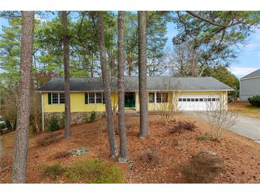 Charming yellow ranch-style house with green trim, nestled among tall pine trees and a well-manicured yard at 2142 Graystone Pkwy, Grayson, GA 30017