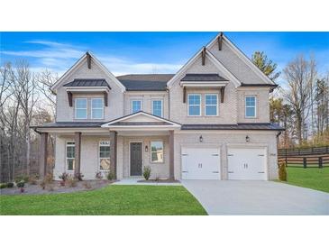 Charming two-story home with a white brick exterior, two-car garage, and a well-manicured front yard at 2018 Stonecreek Dr, Woodstock, GA 30188