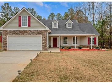 Charming single-Gathering home boasts stone accents, two-car garage, red door and shutters, and landscaped front yard at 10 Oakbrook Ln, Covington, GA 30016