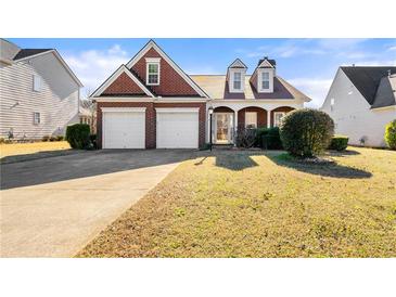 Charming brick home featuring a two-car garage, well-maintained lawn, and inviting front porch at 3296 Quincey Xing, Conyers, GA 30013