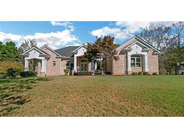 Expansive ranch home featuring a brick exterior, a large lawn, and stately architectural details at 6740 Mountain Lake Ln, Cumming, GA 30028