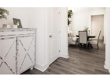 Bright hallway featuring light gray floors, a white cabinet, white doors, and an adjacent dining area at 2456 Honey Way, Conyers, GA 30013