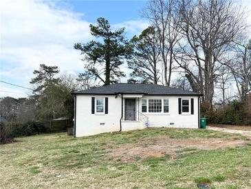 Charming brick home featuring black shutters, a well-manicured lawn, and mature trees, offering a serene and inviting curb appeal at 4206 Sherwood Ave, Decatur, GA 30035