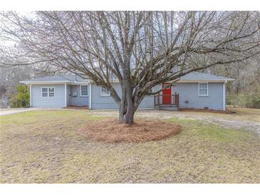 Charming single-story home with mature tree, grey paint and red door at 6297 Temple St, Lithia Springs, GA 30122