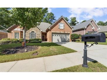 Charming brick home features a manicured lawn, stone accents and a two-car garage at 2110 Retreat Haven Ln, Dacula, GA 30019