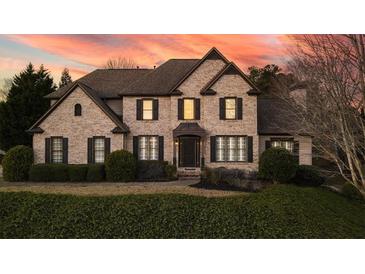 Charming brick home featuring a manicured lawn and a welcoming front facade at sunset at 520 Waterside Ct, Canton, GA 30114