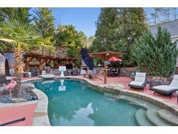 Inviting backyard pool with lush landscaping and comfortable lounge seating creating a private outdoor oasis at 971 Hendon, Woodstock, GA 30188