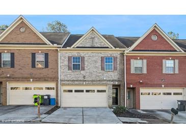 Townhome exterior with brick facade, attached garage, and well-maintained landscaping at 323 Sweetshrub Dr, Austell, GA 30168