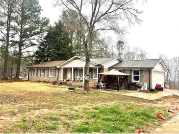 Charming brick home with covered porch and gazebo, nestled among mature trees on a spacious lot at 3750 Dial Mill Ne Rd, Conyers, GA 30013